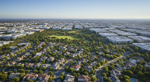 Aerial view of mixed residential neighborhoods and business parks surrounded by trees.